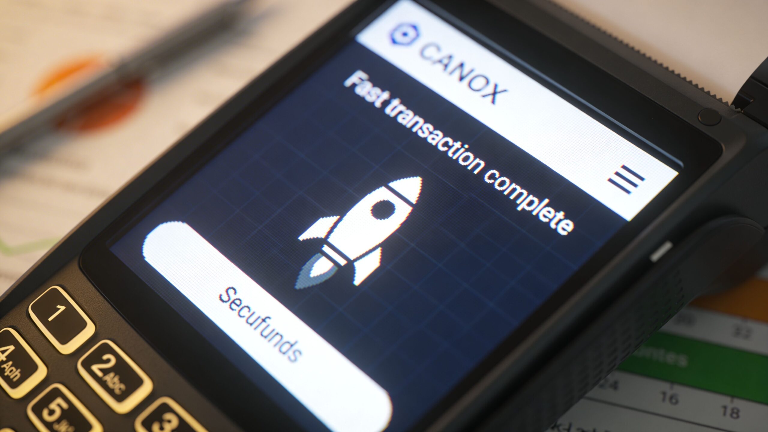 A handheld payment terminal displaying a successful transaction message with a rocket icon for the brand Secufunds.